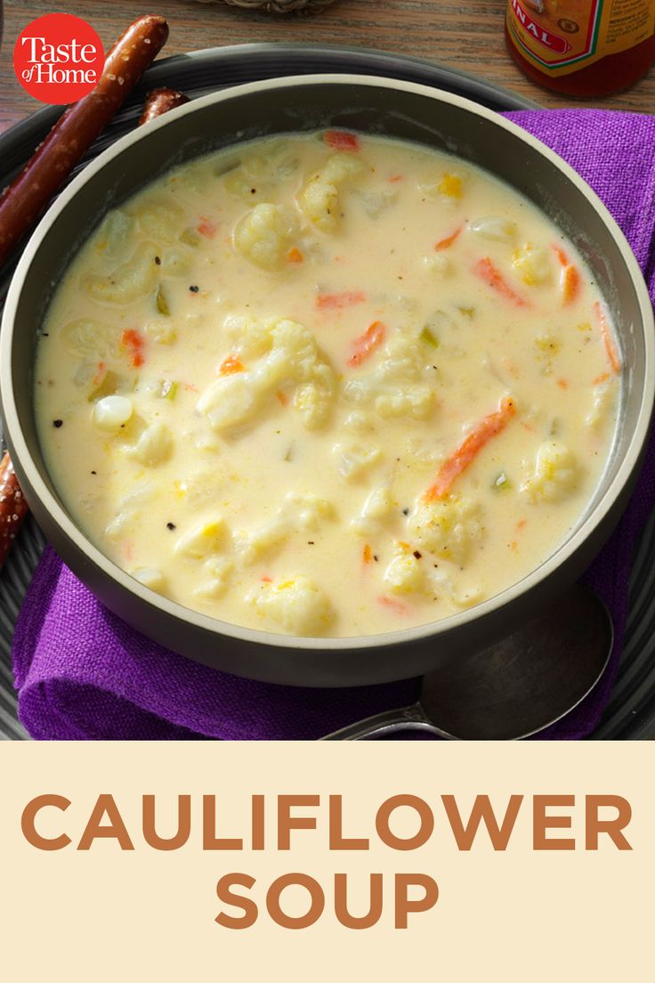 a bowl of cauliflower soup on a plate with a hot dog next to it