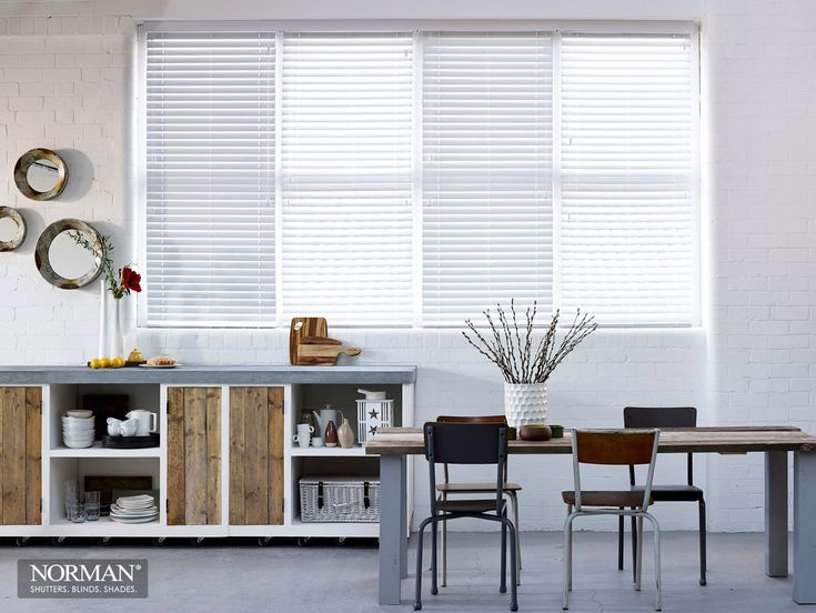 a dining room table and chairs in front of a window with blinds on the windowsill