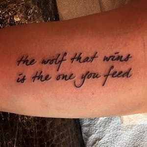 a person with a tattoo on their arm that says, the wolf that wants is the one you feed