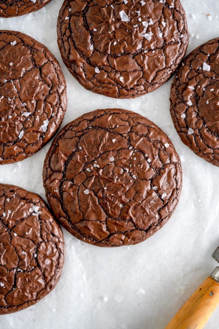 chocolate cookies with powdered sugar on top sitting on parchment paper next to a knife