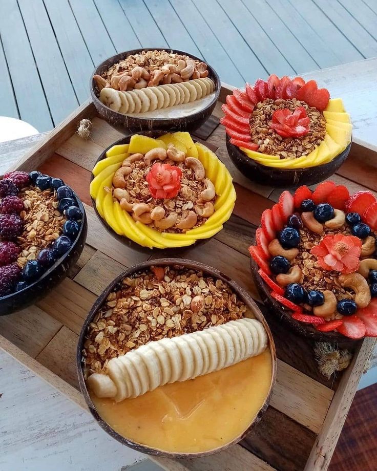 several desserts are arranged in bowls on a wooden tray, ready to be eaten