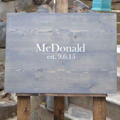 a wooden sign sitting on top of a stone steps next to flowers and potted plants