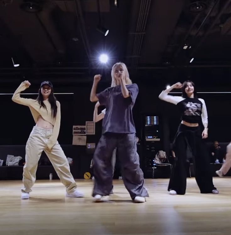 several people are dancing on the floor in an indoor dance studio, some with their arms raised