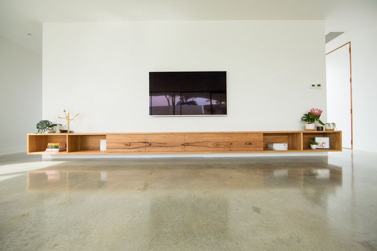 an empty living room with white walls and large wooden shelf on the wall, filled with potted plants