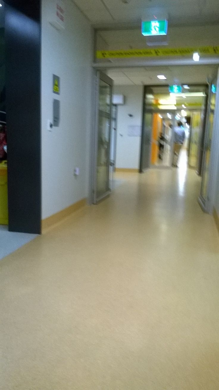 an empty hallway with some people walking down the hall and one person is in the distance