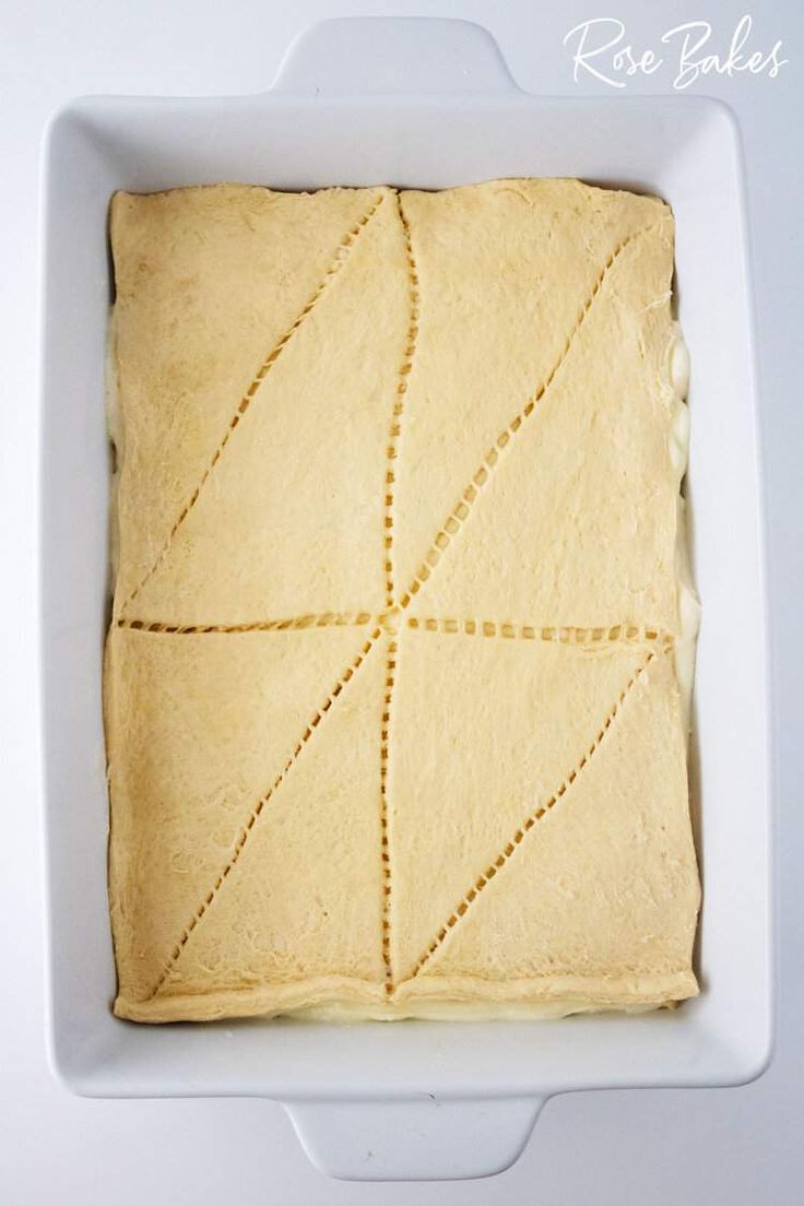 a square cake in a white dish with yellow icing on top and lines drawn across the edges