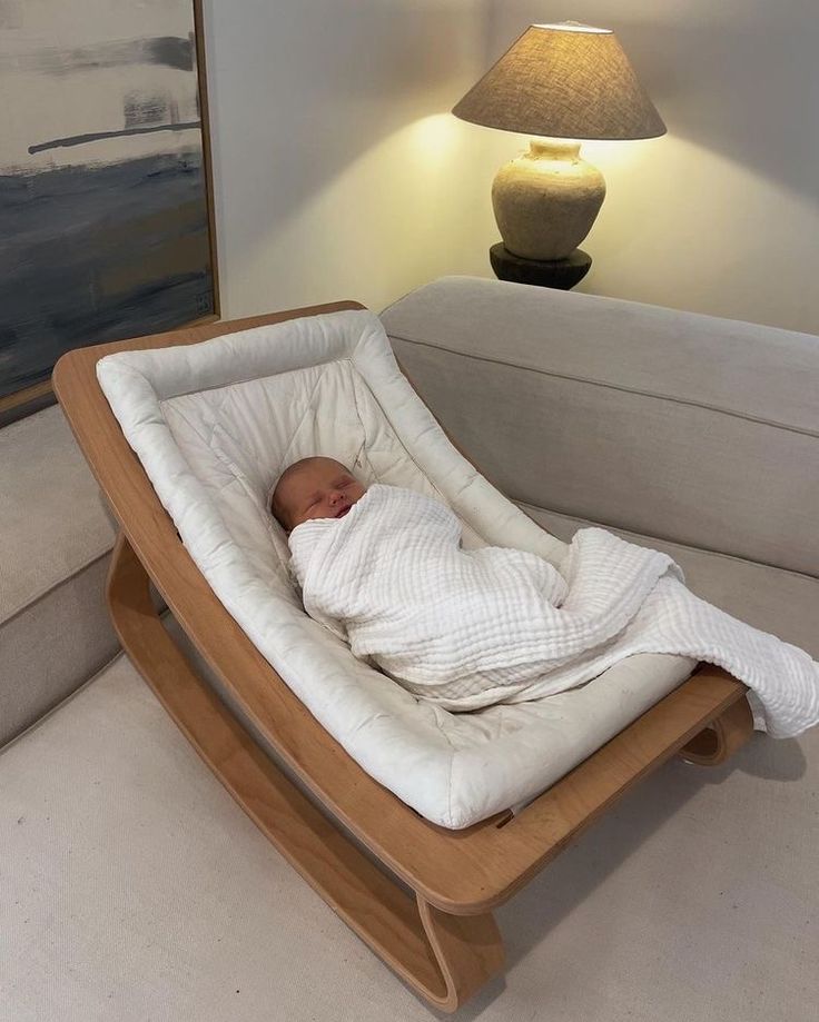 a baby is laying in a rocking chair with a blanket on it's back