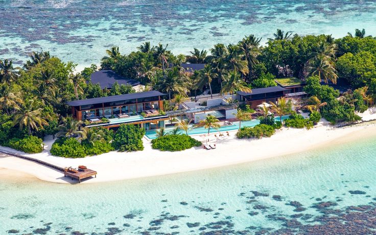 an aerial view of a tropical island in the middle of the ocean with a house on it