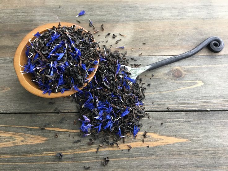 two wooden spoons filled with blue and black sprinkles on top of a wooden table