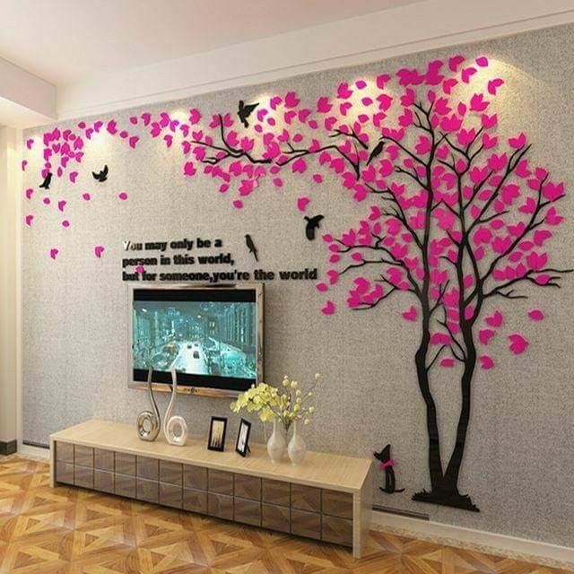 a living room decorated with pink and black tree decals on the wall, along with a tv