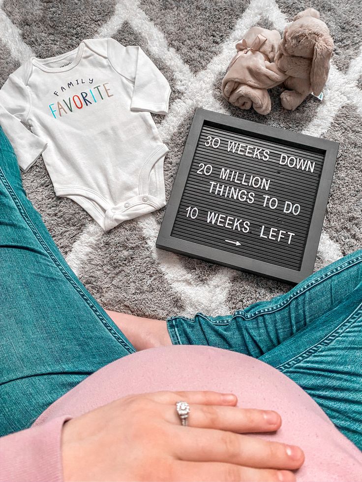 a pregnant woman laying on the floor next to her baby's birth announcement sign