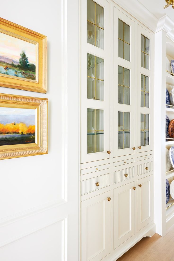 a white china cabinet filled with blue and white dishes