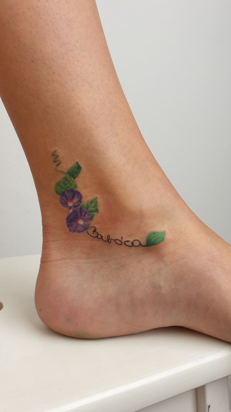 a woman's foot with flowers on it and the word love written in cursive writing