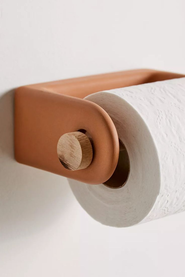 a roll of toilet paper is hanging on the wall next to a brown leather holder