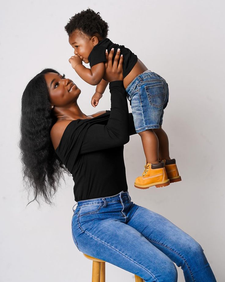 a woman sitting on a stool holding a small child