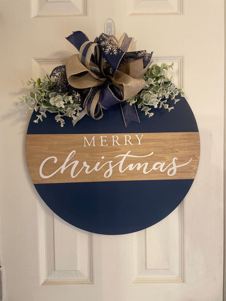 a merry christmas door hanger on the side of a white door with blue and tan stripes