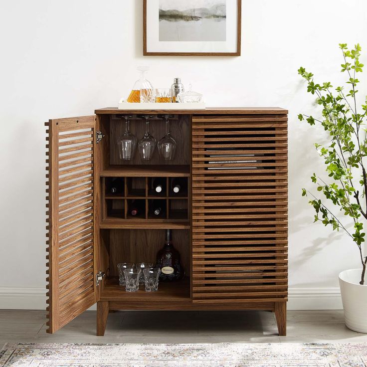 a wooden cabinet with wine glasses on it and a potted plant in the corner