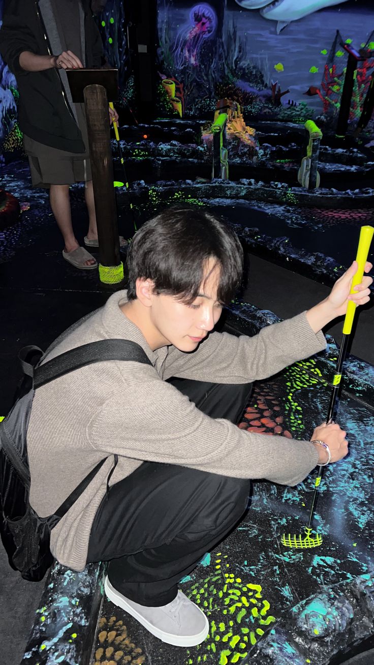 a young man kneeling on top of a skateboard holding a yellow object in his hand