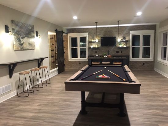 a pool table in the middle of a room with bar stools and tv on the wall