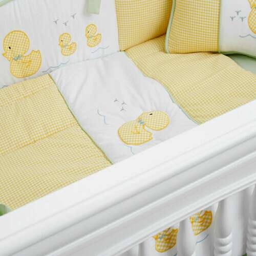 a baby crib with yellow ducky bedding and pillows on the bottom row