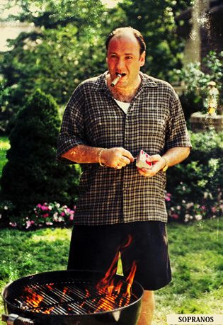 a man standing in front of an open fire pit with his tongue out and holding something to his mouth