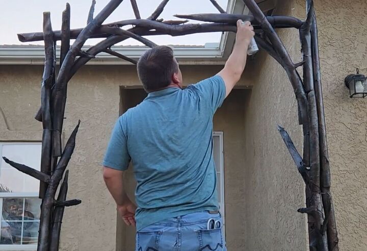 a man is working on some kind of structure outside his house that has been made out of branches