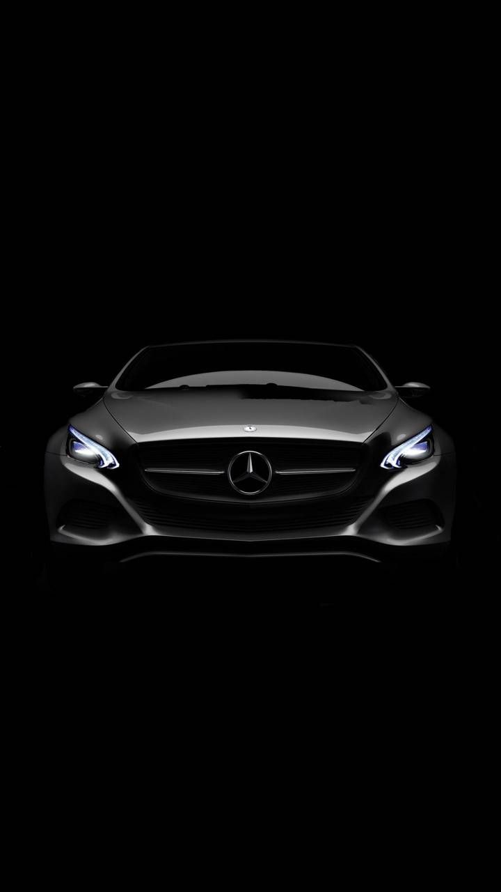 the front end of a black mercedes sports car in the dark with its headlights on