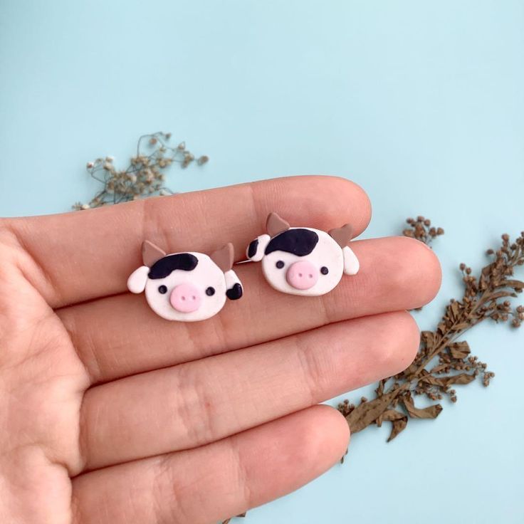 a person is holding two tiny cow earrings