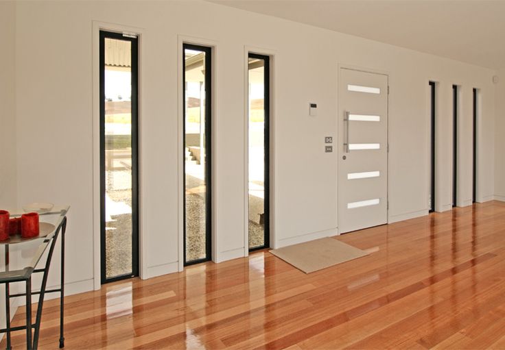 an empty room with wood flooring and white walls is seen in this image, there are three red candles on the table next to the door