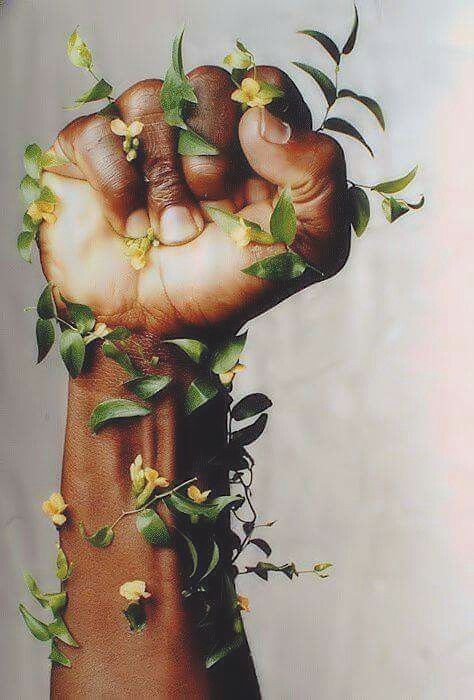 a person holding up their fist with flowers growing out of the top and bottom of it