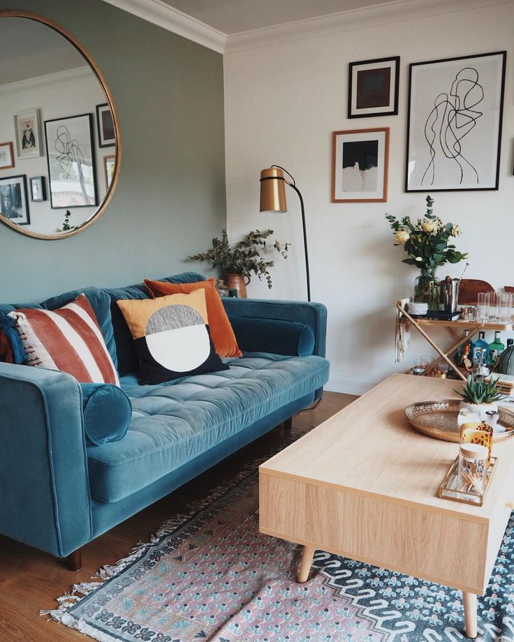 a living room with blue couches and pictures on the wall above it, along with a coffee table