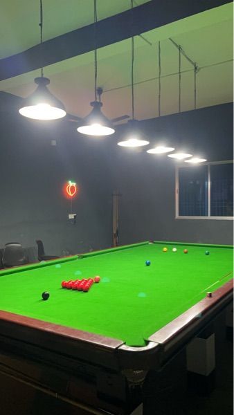 a green pool table in a room with lights