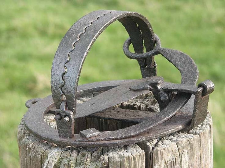 an old rusted metal object sitting on top of a wooden post in the grass