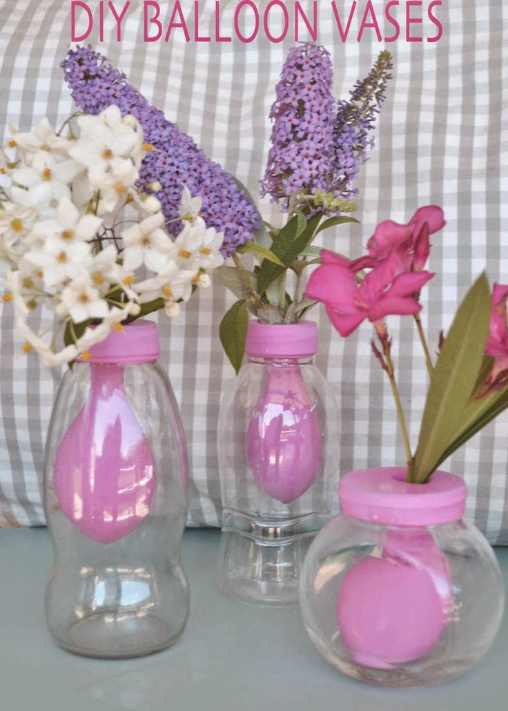 three vases with flowers in them sitting on a table next to a checkered pillow