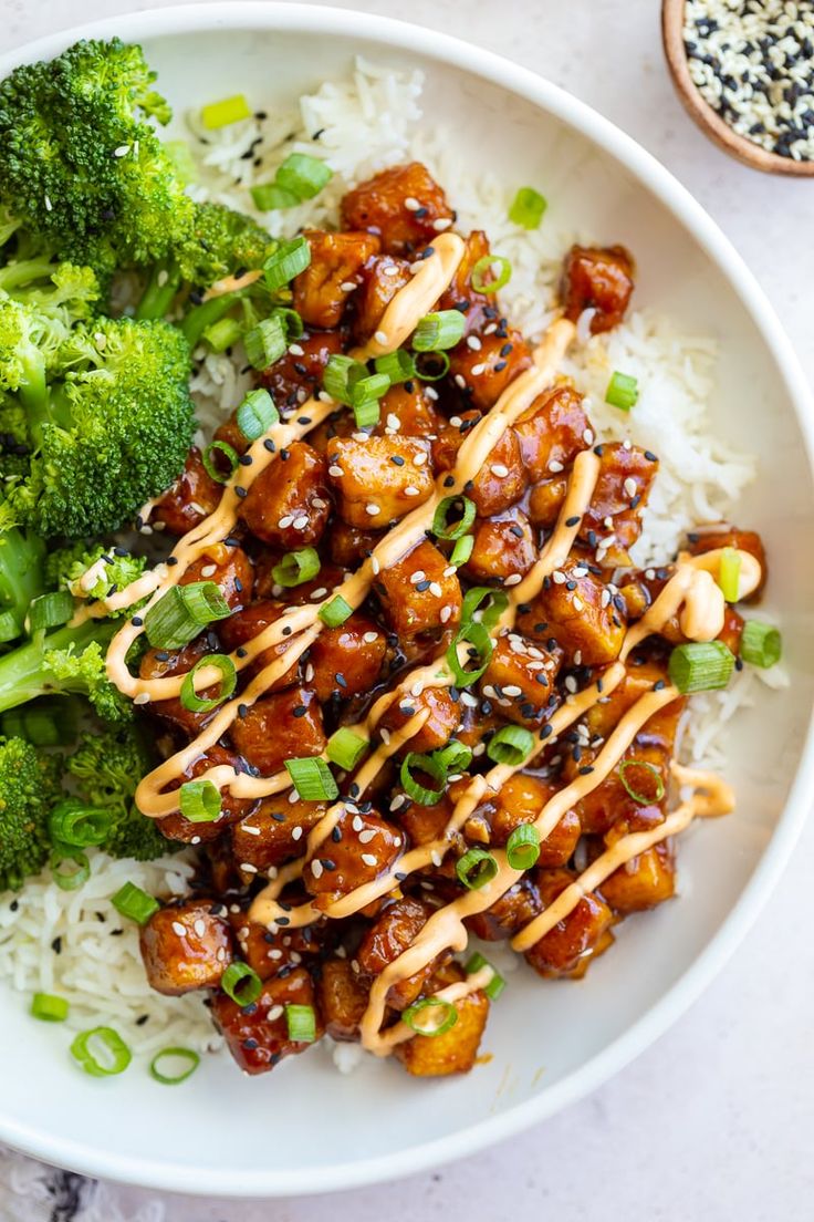 a white plate topped with chicken and broccoli covered in teriyaki sauce