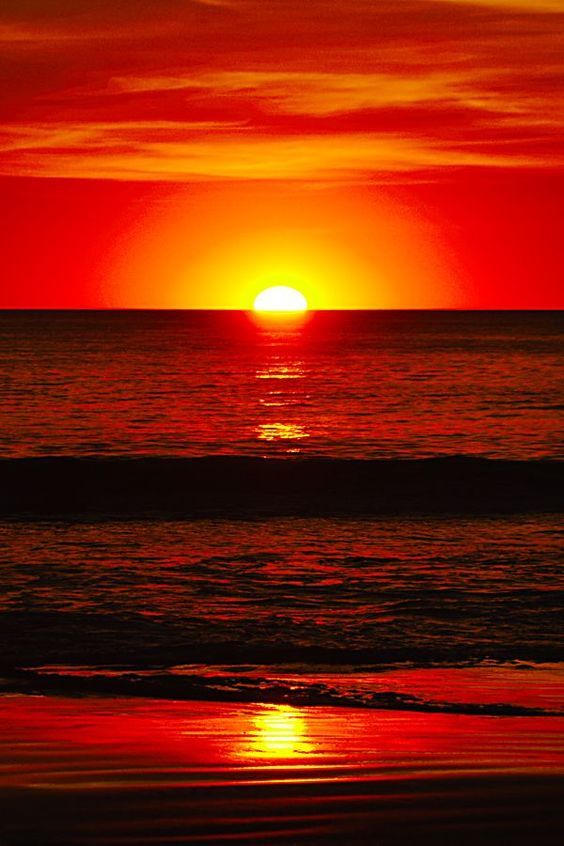 the sun is setting over the ocean with red and orange colors in it's sky