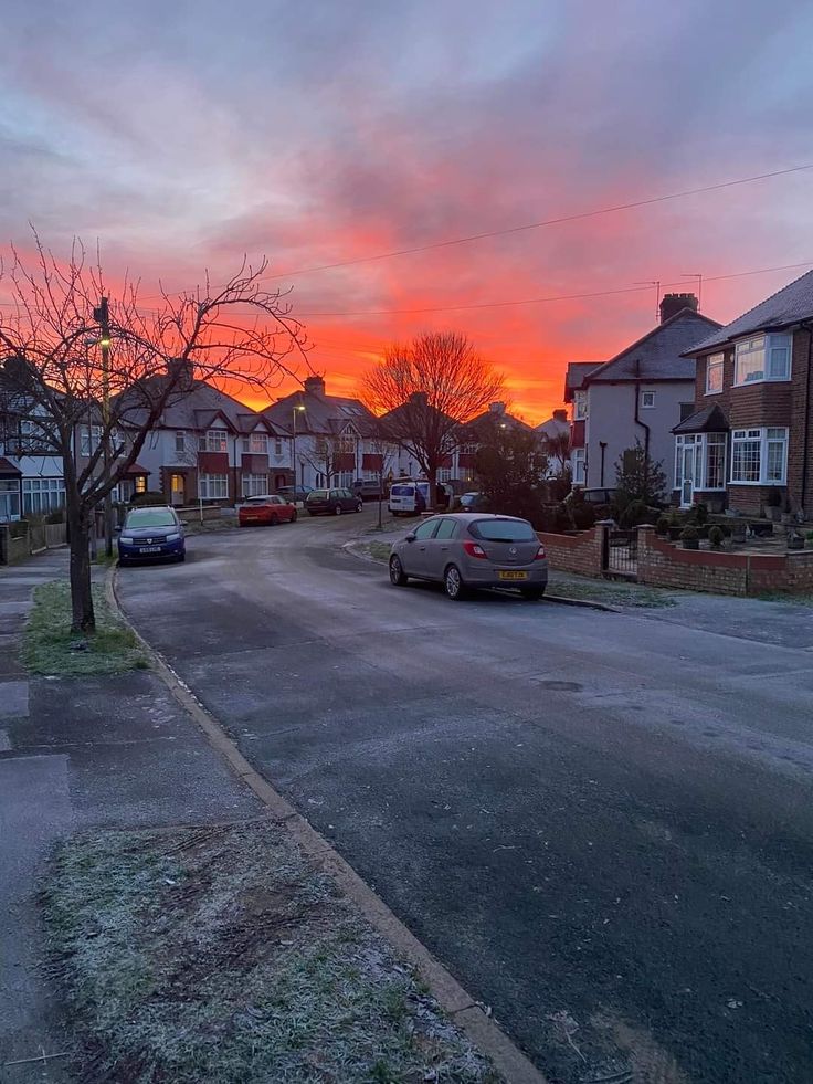 cars parked on the street in front of houses at sunset