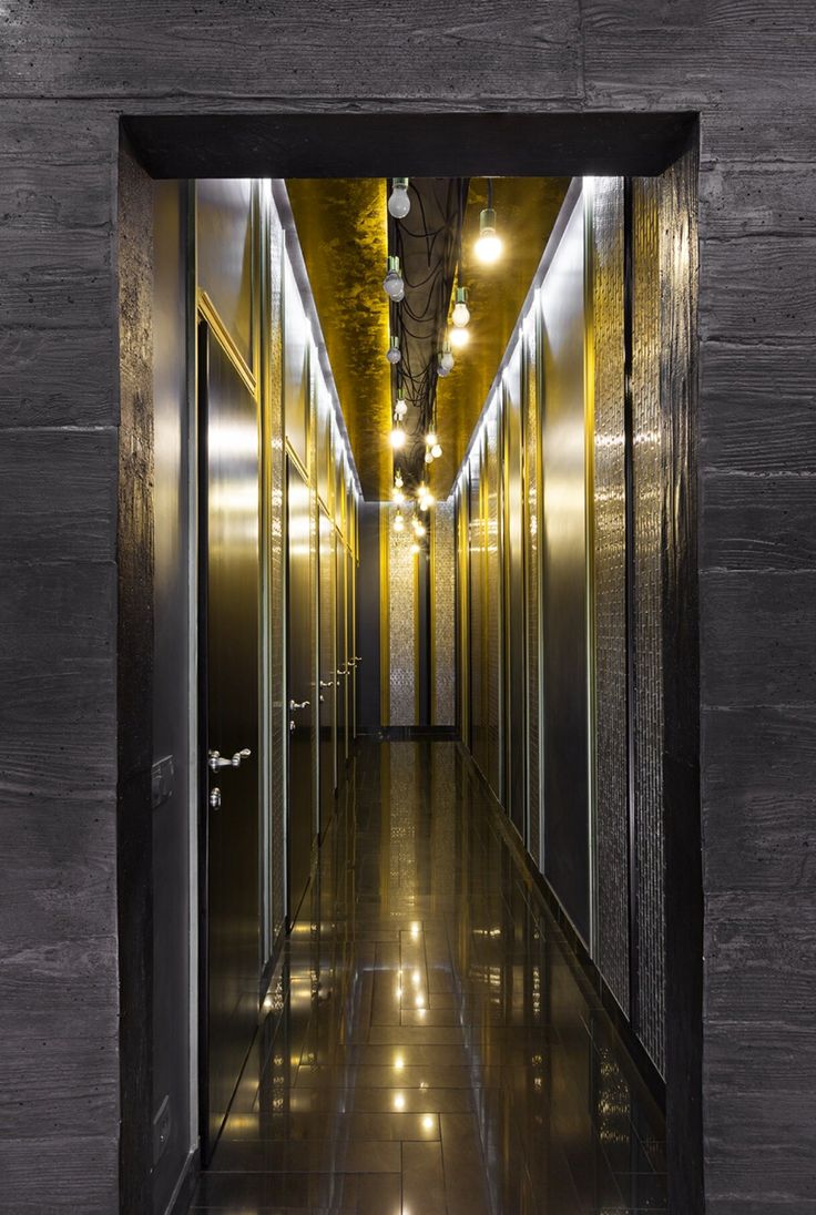 an empty hallway with metal doors and lights on the ceiling is lit by recessed lighting