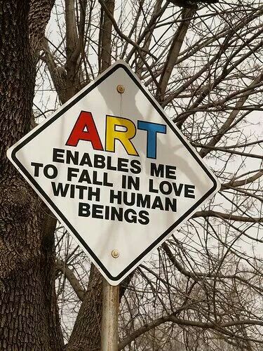 a street sign that says art enables me to fall in love with human beings