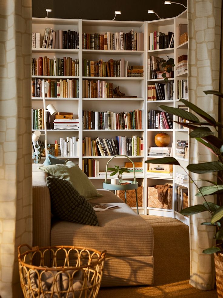 a living room filled with lots of books and furniture next to a wall mounted book shelf