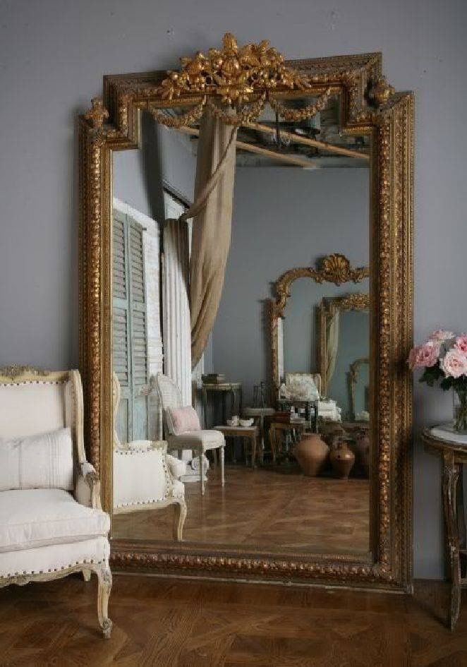 a large mirror sitting on top of a wooden floor next to a chair and table