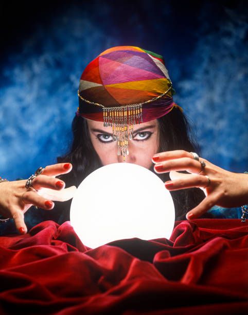 a woman holding a crystal ball in front of her face while wearing a colorful headdress