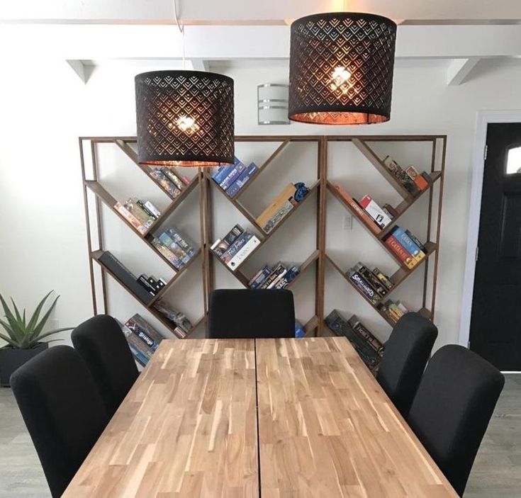 a wooden table surrounded by black chairs and bookshelves