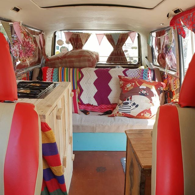 the interior of a camper van with colorful pillows