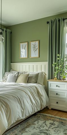 a bedroom with green walls, white bedding and two windows that have curtains on them