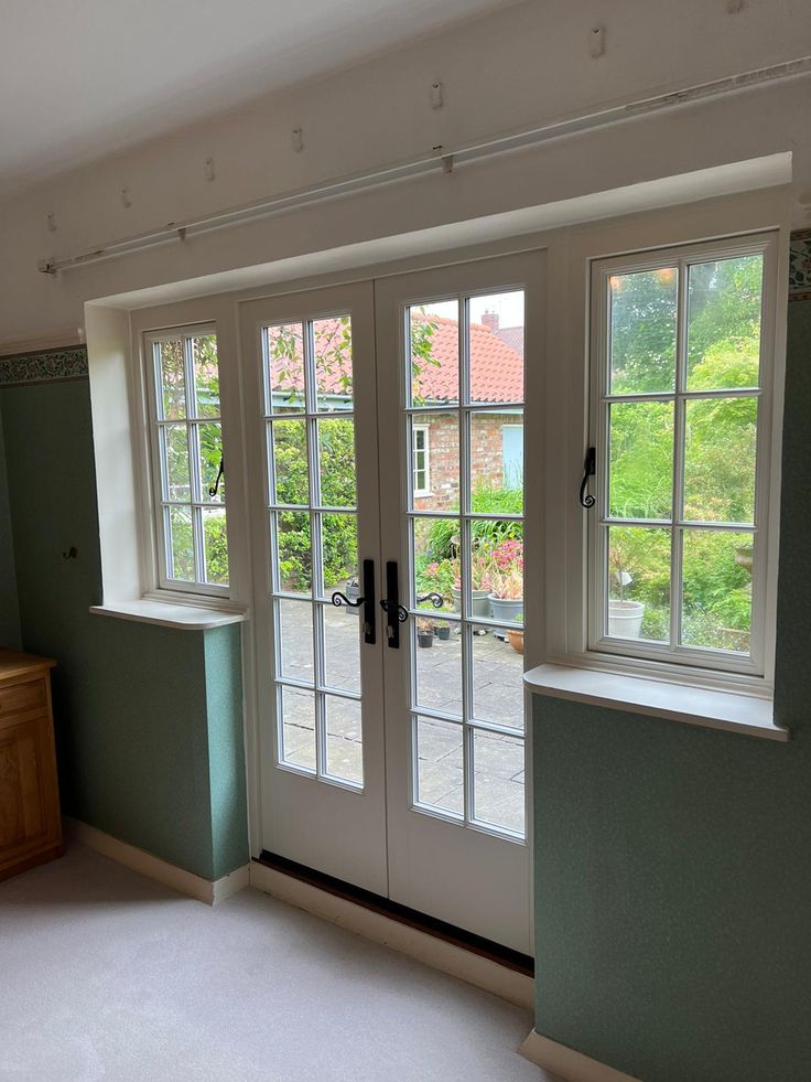 White french doors on the inside of a house with casement windows either side. French Door Exterior Patio, Georgian Patio Doors, Wooden French Windows, French Garden Doors, Georgian French Doors, Kitchen With French Doors To Patio, Door With Window Above, Diy Patio Door, French Doors In Kitchen