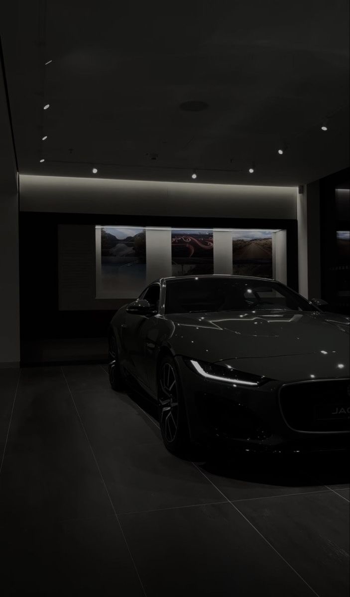 a black car is parked in a dark room with two lights on the side of it