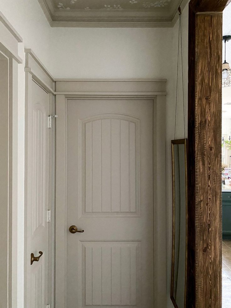 an empty hallway with white walls and wood trim on the door, next to a mirror