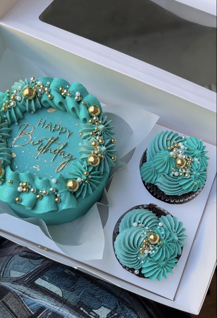 a birthday cake and cupcakes in a box