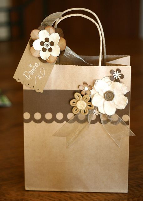 a brown and white paper bag with flowers on the front, sitting on a wooden table